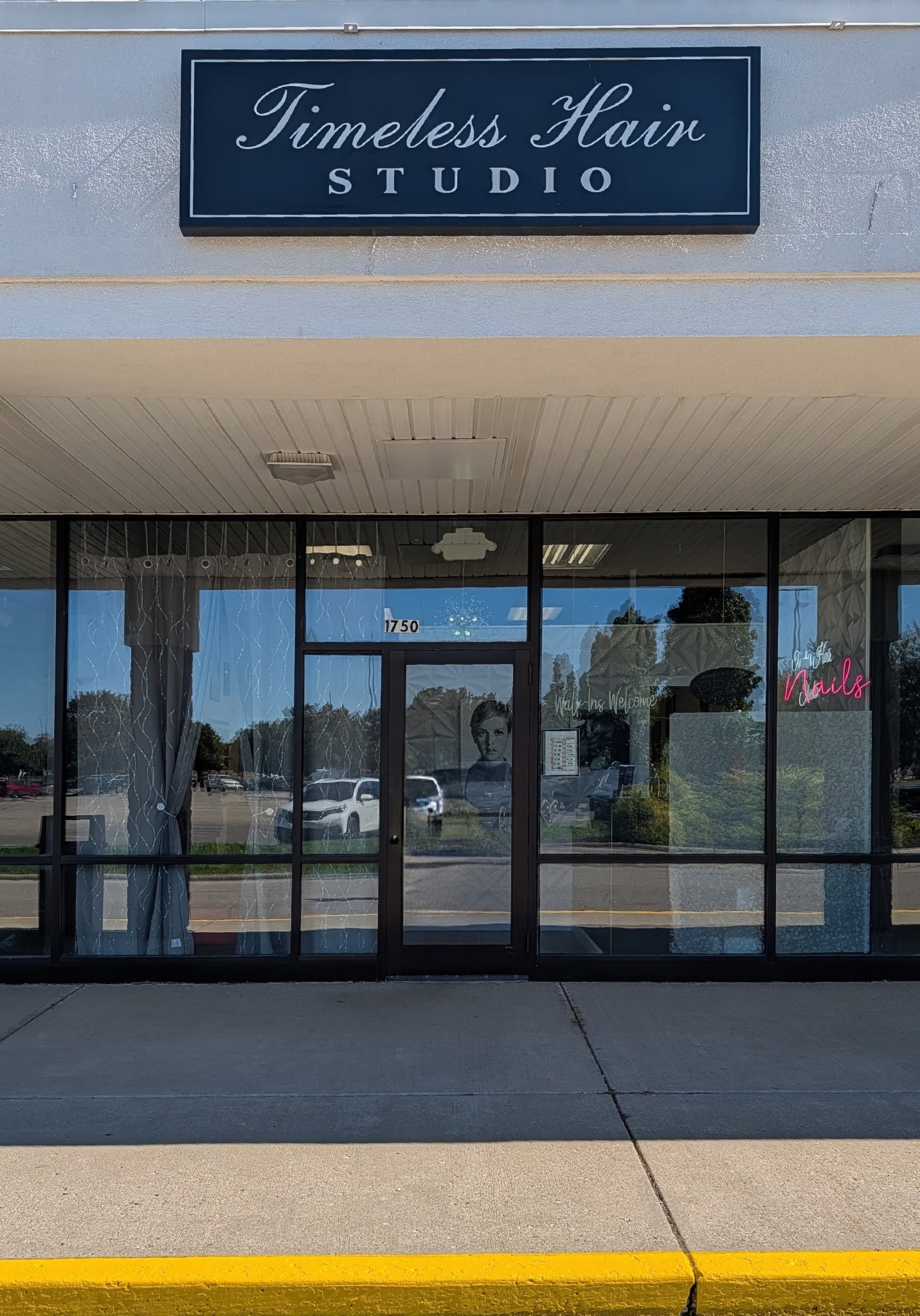 The main entrance of Timeless Hair Studio at 1750, with the navy Timeless Hair Studio sign above the glass storefront and a pink neon Nails sign in the window