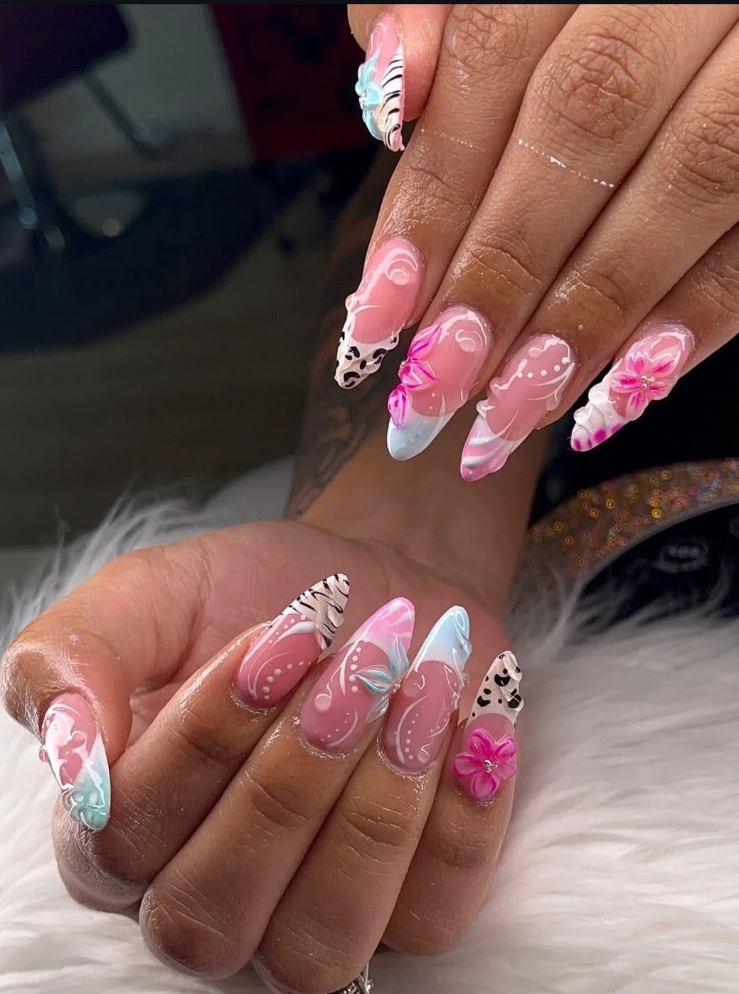 Almond-shaped nails with pink flowers, animal-print tips, and hand-painted swirls